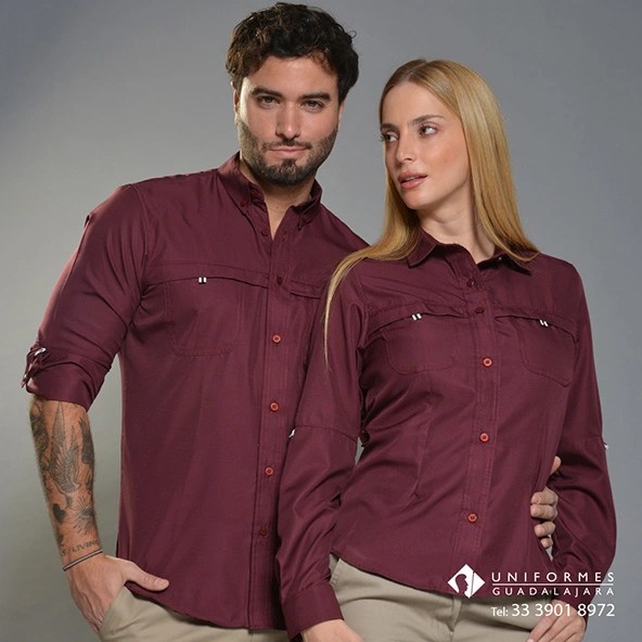 Foto 1 (pareja, camisas color vino, fondo gris) Texto alternativo: Camisas para uniformes outdoor color vino, modelo dama y caballero, manga larga con bolsillos frontales.