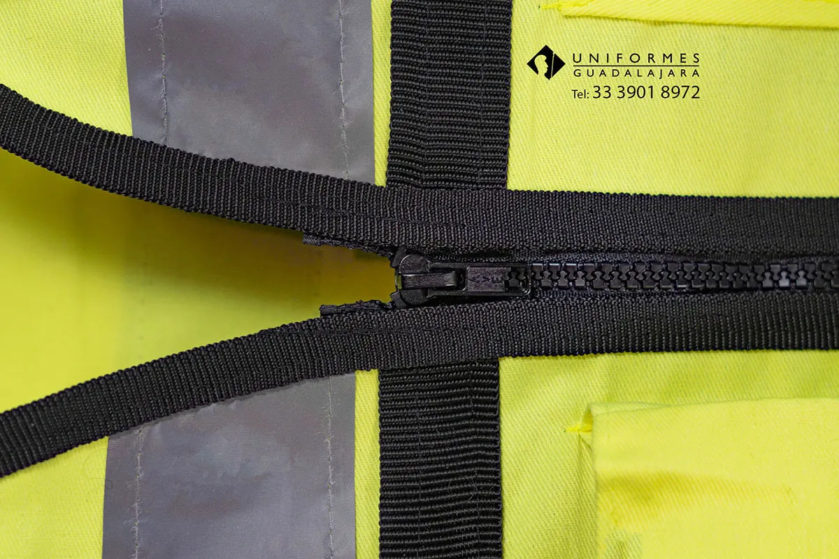 Detalle de chaleco brigadista amarillo neón con cierre y cinta reflejante para uso en empresas y operaciones de seguridad